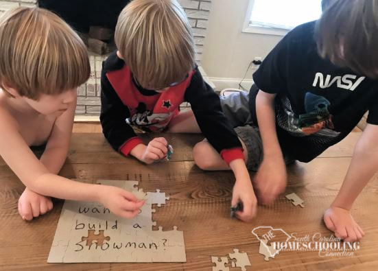 Boys working together to solve a puzzle with a treasure hunt clue written on the back. 