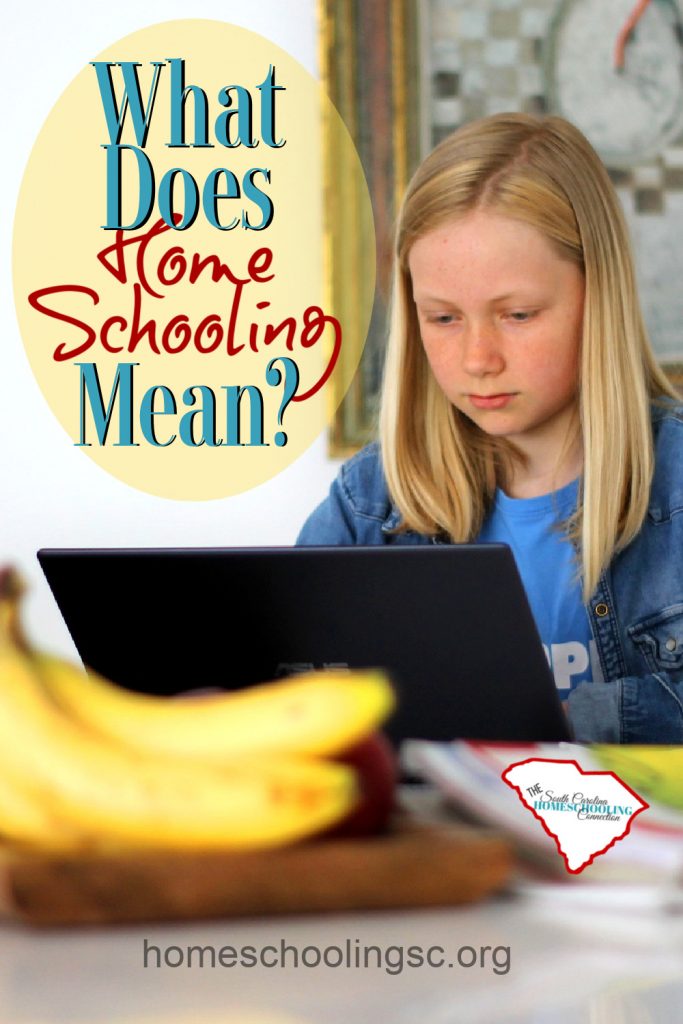 Girl working on laptop computer at kitchen table. What is homeschooling?